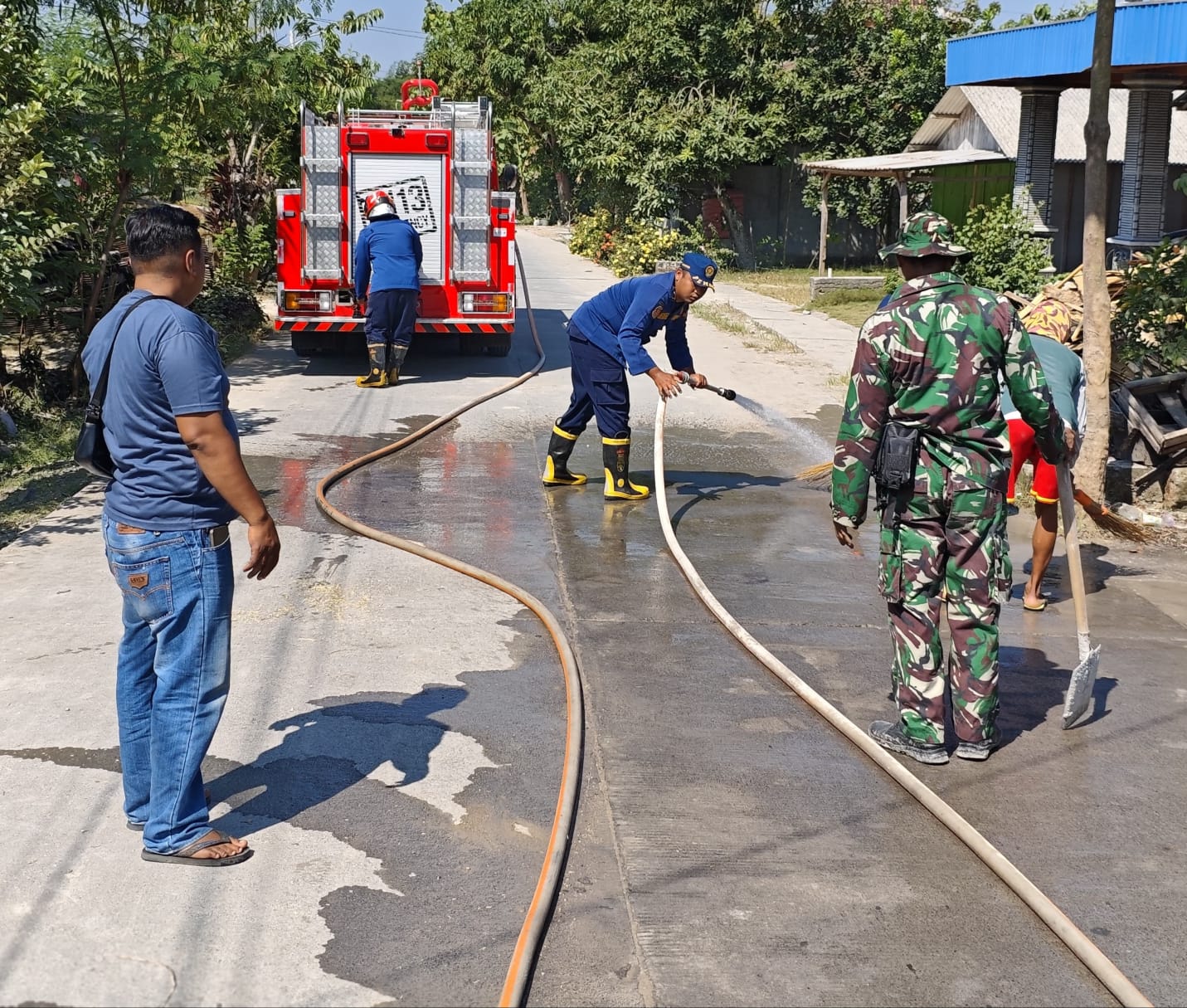Damkarmat Bojonegoro Lakukan Penyemprotan Material Tanah Uruk di Jalan Poros Desa Tanggungan